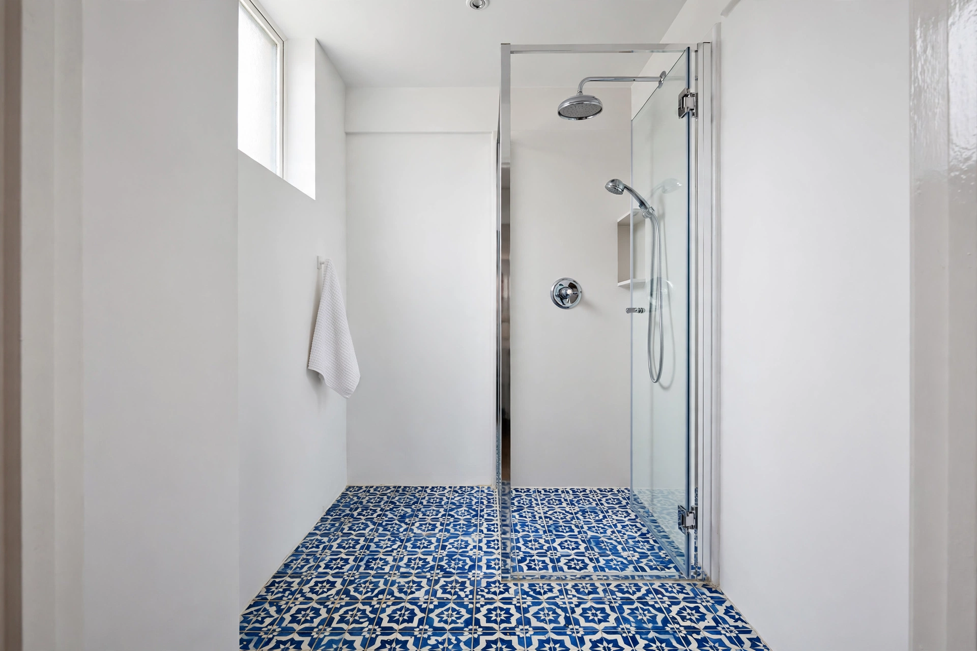 Bold patterned encaustic floor with plain white walls in a small shower